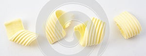 Four Textured Curls of Butter on White Background