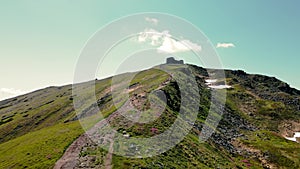 Four tourists with backpacks on their shoulders climb up in the summer. Aerial view from the back. Hiking in the