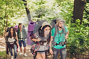 Four tourists got lost in the forest, trying to find the way, looking serious and focused, all having backpacks, mates, all needed