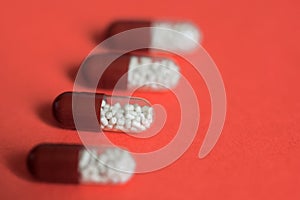 Four transparent capsule tablets with granules on a uniform background. Macro. Living coral. Shallow depth of field. Health and