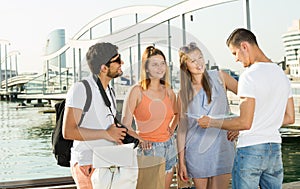 Four travelers holding map in hands