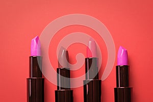 Four tubes of lipstick on a bright red background