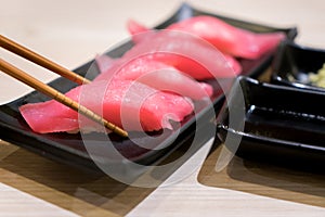 Four tuna sushi with chopsticks in black plate on table at Japanese restuarant. photo