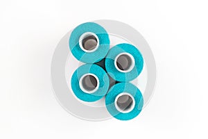 Four turquoise sewing threads on a white coils on a white background. Sewing supplies