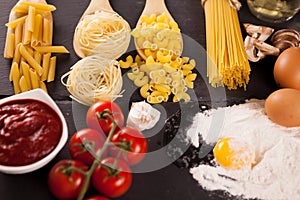 Four types of raw uncooked pasta next to tomatoe souce