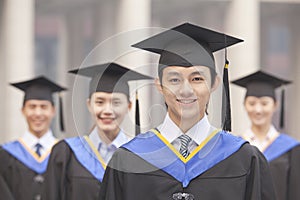 Four University Graduates Smiling, Looking at Camera