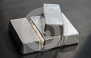 Four unmarked silver bars on a dark background. photo