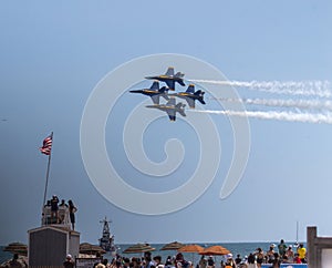 Four US Navy Blue Angels Jets flying in formation over a lifeguard stand at the beach during an airshow