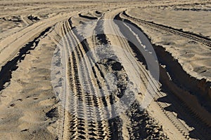 Four wheel drive tracks in sand with vanishing point