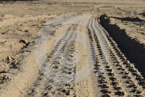 Four wheel drive tracks in soft sand at ground level with vanishing point