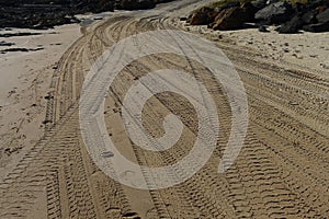 Four wheel drive tracks in sand leading to a ramp