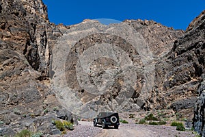 A four-wheel drive vehicle on a dirt road entering a rugged canyon