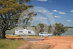 Four wheel drive vehicle and large caravan at roadside stop next to a lake in the outback of Australia