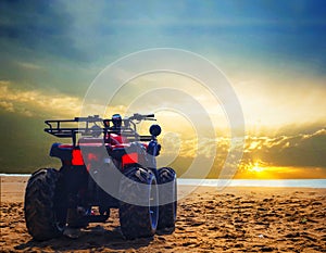 Four wheeler dirt bike on sand of sea beach during sunrise with dramatic colourful sky