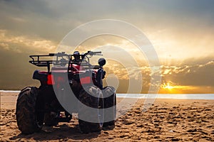 Four wheeler dirt bike on sand of sea beach during sunset