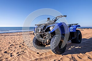 Four wheeler quadbike on sand at beach on bright sunny day