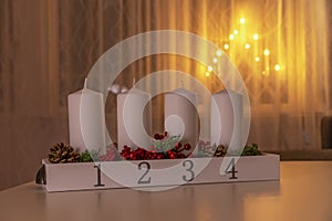 Four white advent candles on table with electic advent candlestick on background, the christmas period, adventsljusstake