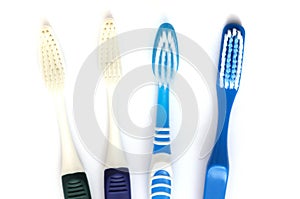 Four white and dark blue toothbrushes against a white backdrop