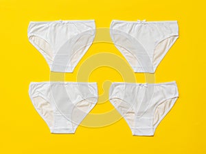 Four white women`s panties on a yellow background. Flat lay