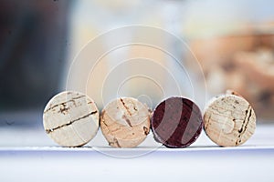 Four wine corks lined up on a table covered in white cloth