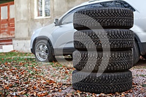 Four winter tyre wheels for changing are near car, copyspace