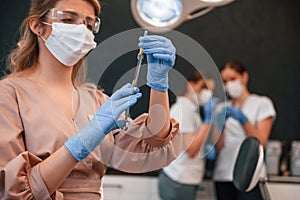 Four women. Doctor holding syringe. In the stomatological cabinet