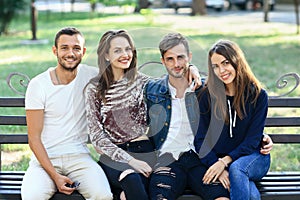 Four women and men sitting on bench in embrace