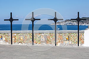 Four wooden crosses with a low wall decorated with religious icons overlooking the sea. Location: Forio, Soccorso`s Church photo