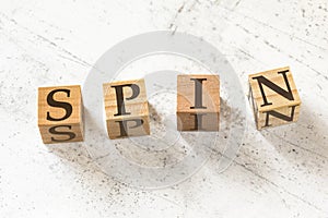 Four wooden cubes with letters SPIN meaning Situation Problem Implication Need on white working board.