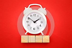 Four wooden cubes with space for text and alarm clock on red background. Time is money concept. Time-limit. Business