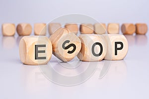 Four wooden cubes with the text 'ESOP' on a light gray background signify a financial concept related to