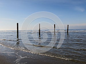 Four wooden poles at the beach in the Northsea Zandvoort, The Netherlands