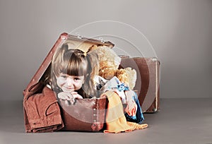 Four-year girl joyfully sits in an old suitcase