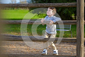 Four year old boy climbing on wooden beams