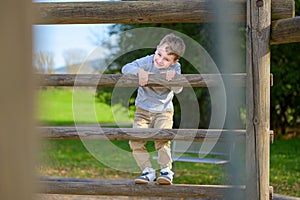 Four year old boy climbing on wooden beams