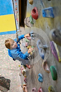 four year old boy climbs the climbing wall in the hall.