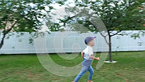 A four-year-old boy joggling barefoot on a green lawn, on the grass, in the courtyard, in summer. laughs, has fun