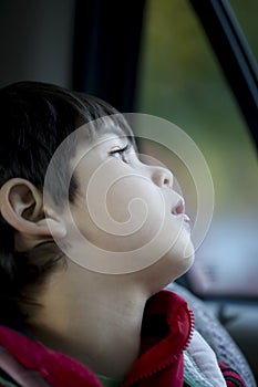 Four year old boy looking quietly out window