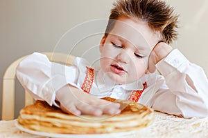 Four-year-old child touches the handle warm pancakes. The holiday of Maslenitsa