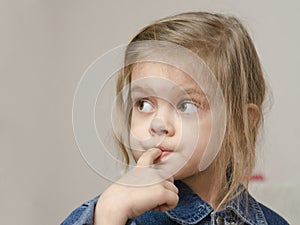 Four-year-old girl with a finger in mouth look left
