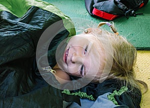 A four-year-old girl lies inside a tourist tent. Morning at the campsite