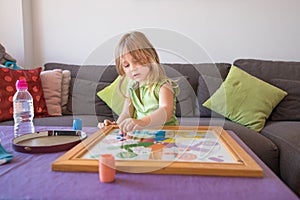 Little child playing parchis game at home in summer photo
