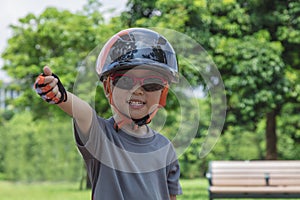 A four years old boy wearing sunglasses, a bike helmet