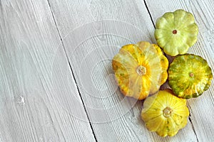 Four yellow and green bush pumpkins on white wood background. Garden,agriculture and farming concept.