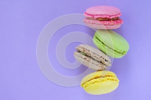 Four yellow, pink, brown and pink biscuit one above the other on violet background with copy space