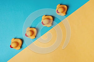 Four yellow rubber ducks on a blue and yellow background. Bath concept. Copy space, flat lay