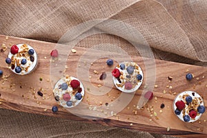 Four Yogurt, Granola and Berries on Wood and Burlap on a Slant