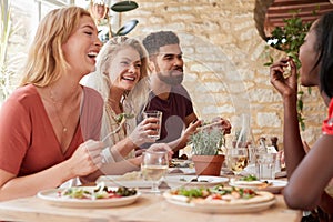 Four young adult friends eating in a restaurant, close up