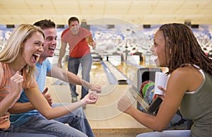 Four young adults cheering in a bowling alley