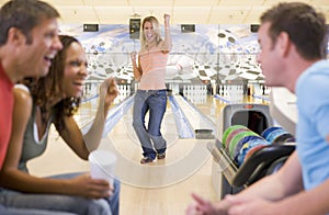 Four young adults cheering in a bowling alley